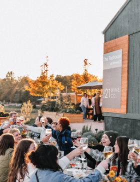 Guests toasting at a long outdoor table with string lights during fall wedding celebration at Retreat 21 near Columbus, Ohio